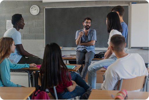 Educator teaching students in front of chalk board.